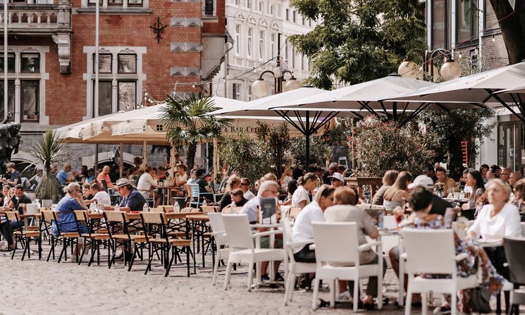 Menschen in den Cafés am Rathausplatz. Foto: Mittwollen und Gradetchliev