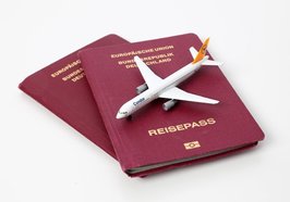 Reisepass mit einem Miniatur-Flugzeug darauf. Foto: Tim Reckmann/Pixelio