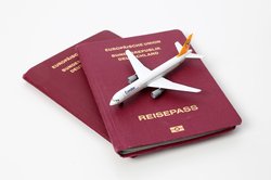 Reisepass mit einem Miniatur-Flugzeug darauf. Foto: Tim Reckmann/Pixelio
