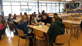 Die Schülerinnen und Schüler sitzen in einer Schulmensa an Tischen. Foto: Anja Czibulinski