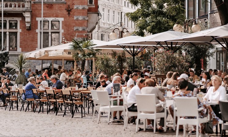 Menschen in den Cafés am Rathausplatz. Foto: Mittwollen und Gradetchliev