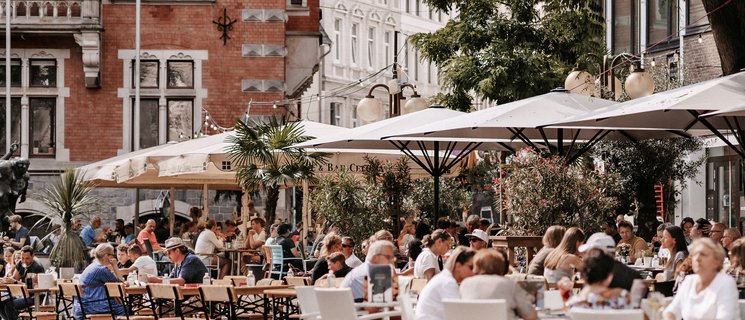 Menschen in den Cafés am Rathausplatz. Foto: Mittwollen und Gradetchliev