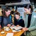 Vorschau: Ein Junge durchstöbert interessiert die Broschüre „ISEK Zukunft 2050“ mit seiner Mutter und einer Mitarbeiterin des Stadtplanungsamtes. Foto: Hauke-Christian Dittrich