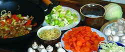 Wokgemüse. Foto: Heidrun Schneider/Pixelio.de Links im Bild ein Wok mit Gemüse, daneben stehen Teller und Schüsseln mit geschnittenem Gemüse. Foto: Heidrun Schneider/Pixelio.de