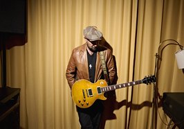 Der Musiker Henrik Freischlader vor einem Vorhang