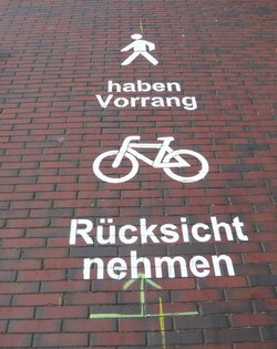 Piktogramm an der Hafenpromenade: Ffußgängerinnen und Fußgänger haben Vorrang, Radfahrende müssen Rücksicht nehmen. Foto: Stadt Oldenburg