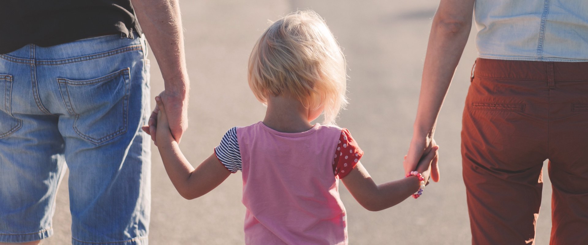 Kind an der Hand von zwei Erwachsenen. Foto: Pexels/Pixabay