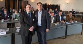 Der stellvertretende Ratsvorsitzende Berndt Benjamins aus Groningen und Oberbürgermeister Jürgen Krogmann stehen nebeneinander. Hinter ihnen sitzen die weiteren Teilnehmenden. Foto: Stadt Oldenburg