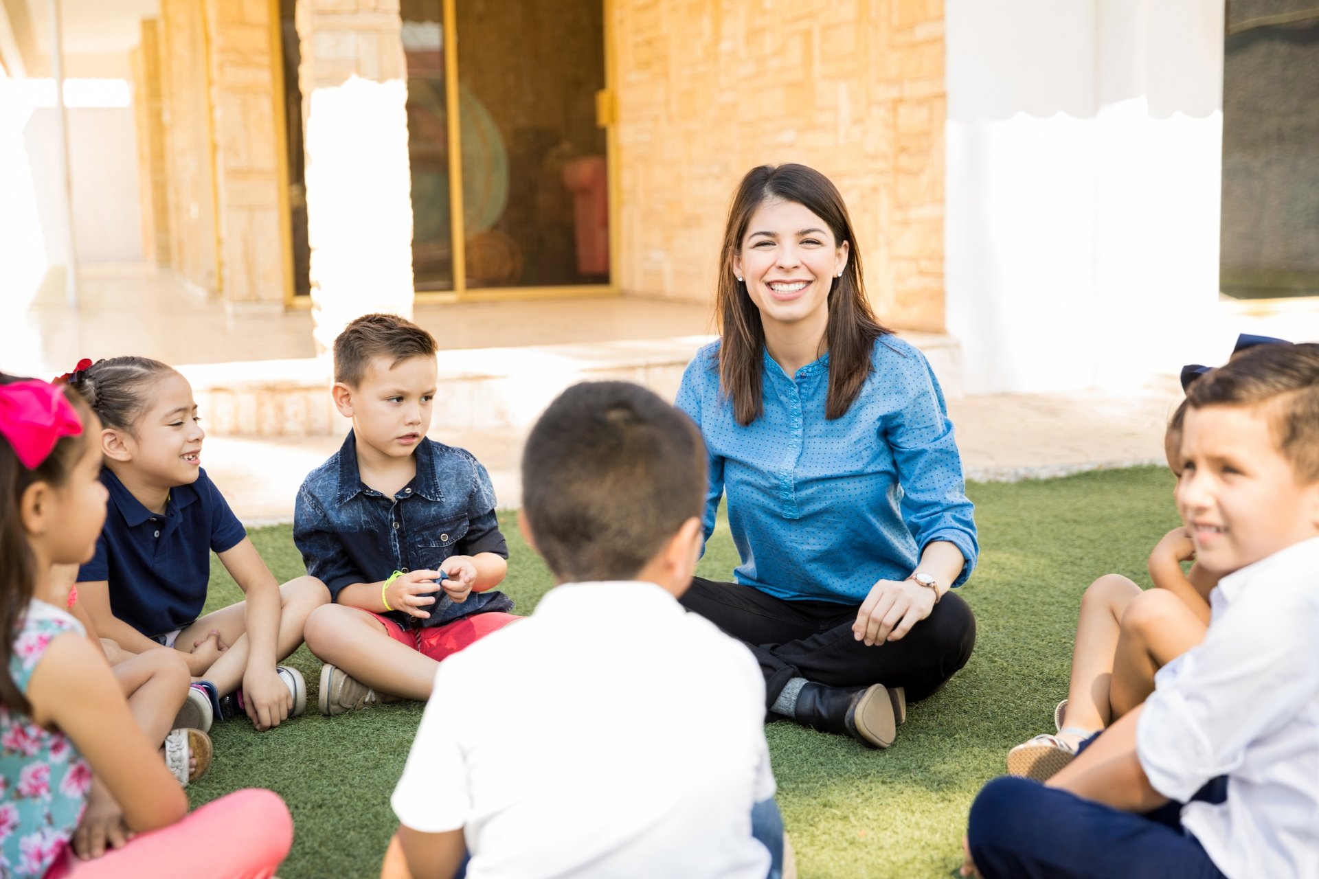 Kinder sitzen mit einer Erzieherin im Kreis. Foto: tonodiaz/Freepik