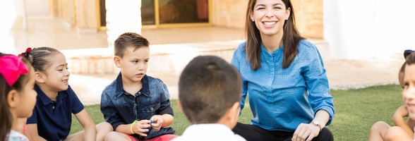 Kinder sitzen mit einer Erzieherin im Kreis. Foto: tonodiaz/Freepik