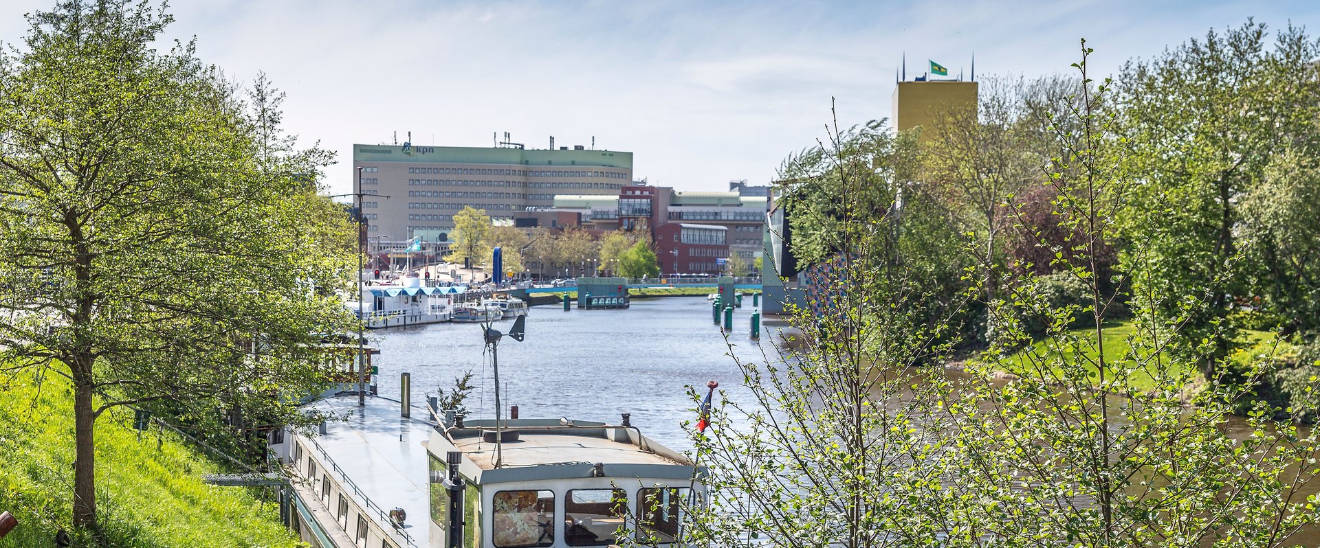 Flussufer in Groningen mit Booten und üppigem Grün an einem sonnigen Tag. Foto: Barbara de Vincent/Pexels