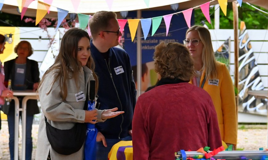 Eine kleine Gruppe unterhält sich lebhaft an einem Stand. Foto: Robert Gertzen