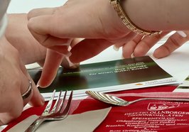 Hände greifen nach der Spendenkarte des „Defftig Ollnborger Gröönkohl-Äten“ in Berlin – ein Moment zwischen Genuss und Engagement. Foto: Torsten von Reeken 