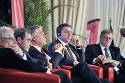 OB Krogmann und Cholets Bürgermeister Gilles Bourdouleix (3. v.l.)beim deutsch-französischen Wirtschaftstag in Cholet. Foto: Etienne Lizambard OB Krogmann und Cholets Bürgermeister Gilles Bourdouleix und andere Menschen sitzen nebeneinander auf einem Podium. Foto: Etienne Lizambard
