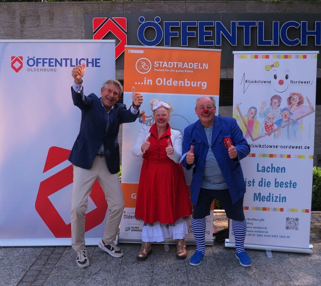 Christian Bunk, Vertriebsdirektor Öffentliche Versicherungen, und zwei Klinikclowns freuen sich auf viele Kilometer zum Erreichen des siebten Etappenziels. Foto: Stadt Oldenburg