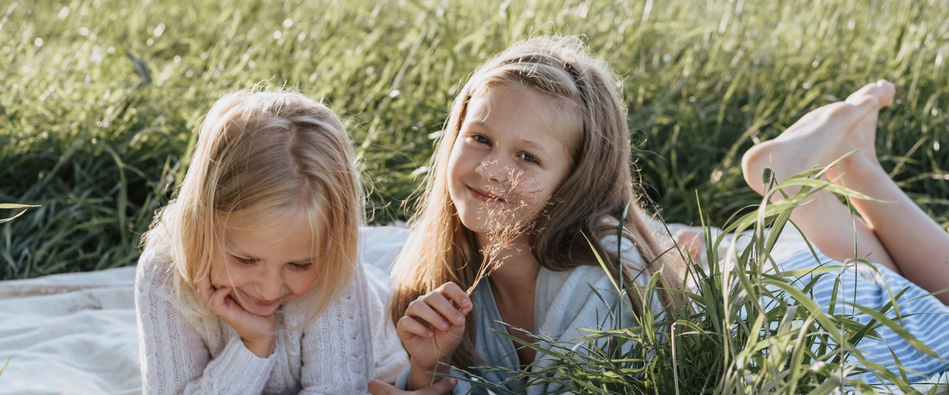 Zwei Mädchen sitzen auf einer Wiese. Foto: Olia Danilevich/Pexels