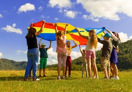 Mehrere Kinder wirbeln mit einem großen Tuch. Foto: Artem Kniaz/Unsplash