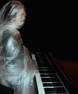 Eine Frau unter einer Plastikfolie spielt Klavier. Foto: Gila Schmidt/Kiyan Naderi Eine Frau unter einer Plastikfolie spielt Klavier. Foto: Gila Schmidt/Kiyan Naderi