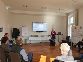 Die Teilnehmenden am Marktdialog sitzen im Halbkreis, Moderatorin Dr. Anke Butscher präsentiert. Foto: Stadt Oldenburg Die Teilnehmenden am Marktdialog sitzen im Halbkreis, Moderatorin Dr. Anke Butscher präsentiert. Foto: Stadt Oldenburg