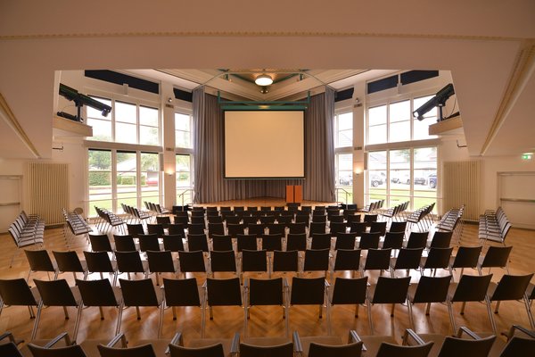 Veranstaltungssaal des PFL mit heruntergelassener Leinwand, Blick vom Eingangstür. Foto: Jörg Hemmen