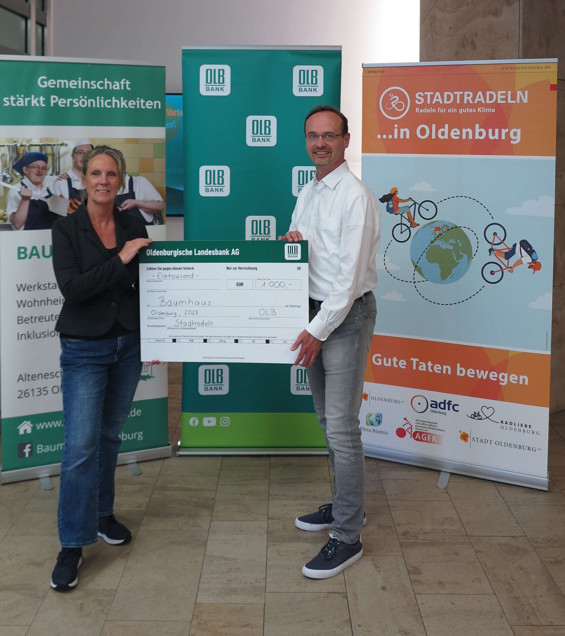 Holger Sandker, Director Head of Sustainability der Oldenburgischen Landesbank AG überreicht den Scheck für das Erreichen des Etappenziels an Bettina Unruh, Geschäftsführerin der Baumhaus gGmbH. Foto: Stadt Oldenburg