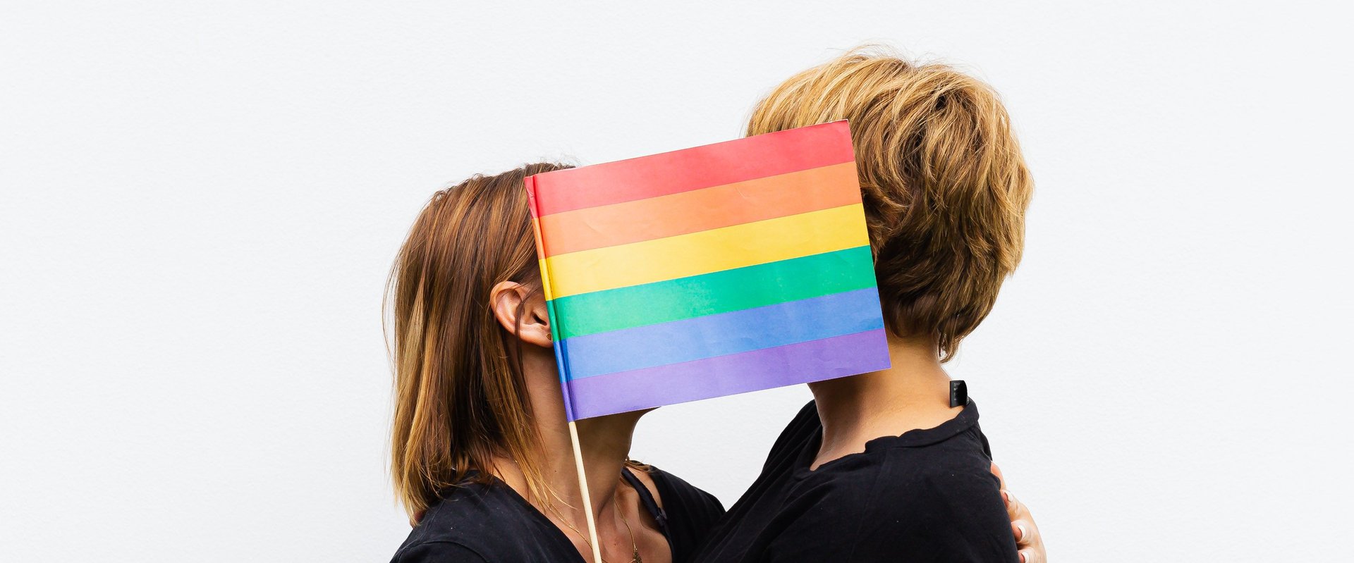 zwei Personen mit Regenbogenflagge. Foto: kaboompics.com/Pexels