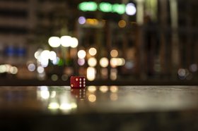 Ein roter Würfel vor verschwommenen Lichtern. Foto: Manfred Mauermann