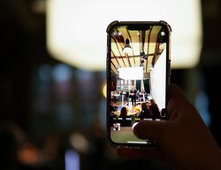 Durch die Handy-Kamera fällt der Blick auf die Aufführung Digitale Pflege. Foto: Christian Striboll