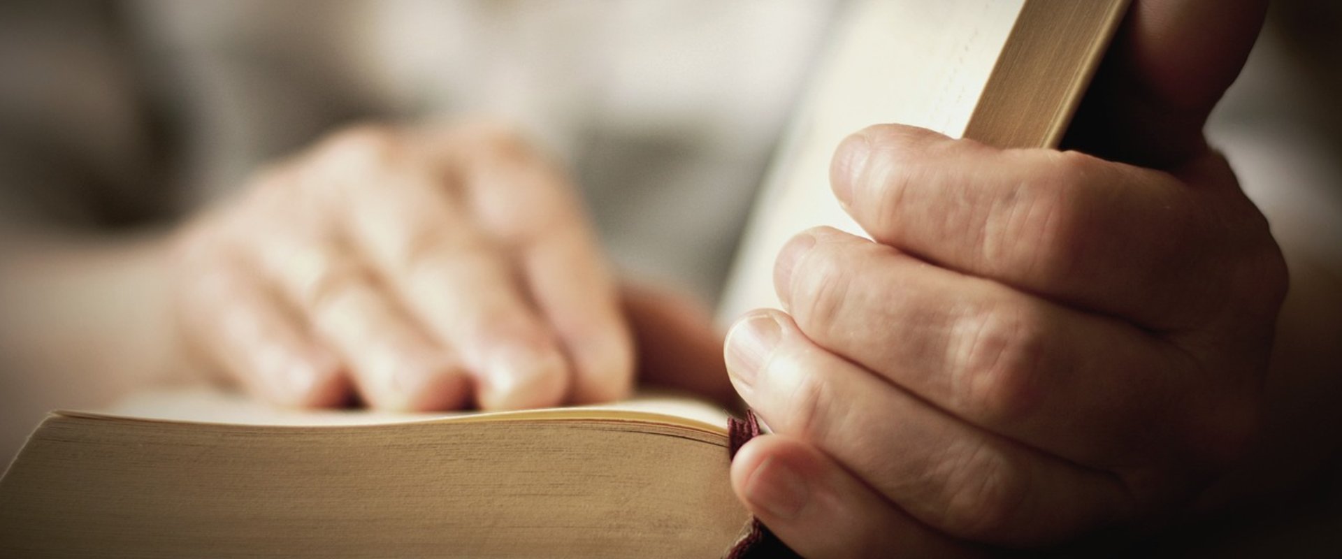 Aus einem geöffneten Buch wird vorgelesen und die Hände liegen auf einer Buchseite. Foto: congerdesign/Pixabay