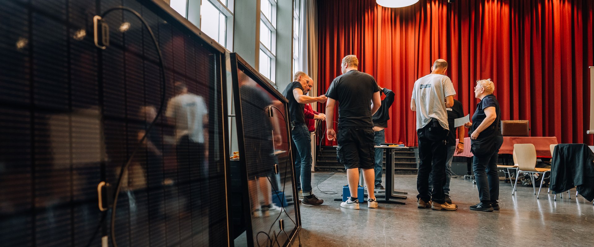 Zu sehen sind zwei Photovoltaik-Module im Vordergrund sowie mehrere Menschen im Hintergrund, die über Kabellängen diskutieren. Foto: Florian Skupin