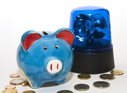 Sparschwein mit Blaulicht und Geld. Foto: Thorben Wengert/Pixelio