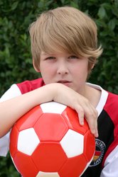 Junge mit einem rot-weißen Fußball. Foto: Alexandra H./Pixelio