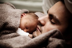 Ein Säugling liegt auf seinem Vater. Foto: publicdomainpictures/pixabay