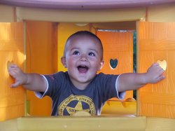 Lachendes Kind schaut durch ein Spielhausfenster. Foto: bodo011/Fotolia.com