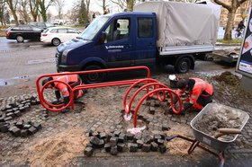 Eine Baustelle, in der zwei Arbeiter eine Konstruktion aus rot lackiertem Stahlrohr im Boden verankert. Foto: Jörg Hemmen