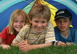 Drei Kinder unter einem Regenschirm. Foto: S. Hofschlaeger/pixelio.de