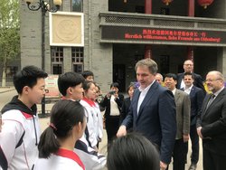 Besichtigung Xi'an No. 89 Middle School, Partnerschule vom AGO. Foto: Stadt Oldenburg Oberbürgermeister Krogmann begrüßt Schülerinnen und Schüler, die Schuluniformen tragen. Im Hintergrund ist ein LED-Spruchband zu sehen mit der Aufschrift „Herzlich willkommen, liebe Freunde aus Oldenburg“. Foto: Stadt Oldenburg