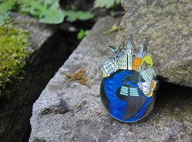 Geocoin mit der Oldenburger Silhouette liegt auf einem Stein. Foto: Stadt Oldenburg