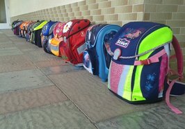 Eine Reihe bunter Schulranzen steht entlang einer Wand. Foto: Volker Oerschkes/pixelio