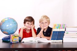 Zwei Schulkinder mit Globus und Büchern. Foto: Kris/Pixabay