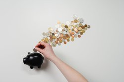 Eine Hand steckt Münzen in ein Sparschwein. Foto: cottonbro/Pexels.com