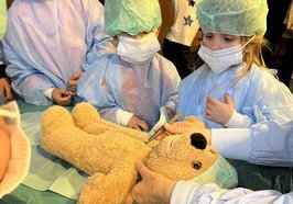 Kinder mit OP-Hauben und -Masken mit ihren Teddybären. Foto: Sascha Stüber