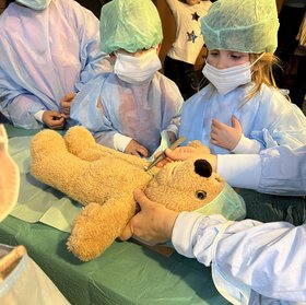 Kinder mit OP-Hauben und -Masken mit ihren Teddybären. Foto: Sascha Stüber