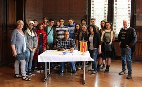 Eine Gruppe Jugendliche und ihre Lehrkräfte steht um einen Tisch. Am Tisch sitzt ein Mann und trägt sich in das Gästebuch ein. Foto: Stadt Oldenburg
