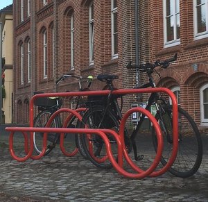 Fahrradständer Tube Line aus rot lackiertem Metall mit angeschlossenen Fahrrädern. Foto: Stadt Oldenburg Fahrradständer Tube Line aus rot lackiertem Metall mit angeschlossenen Fahrrädern. Foto: Stadt Oldenburg