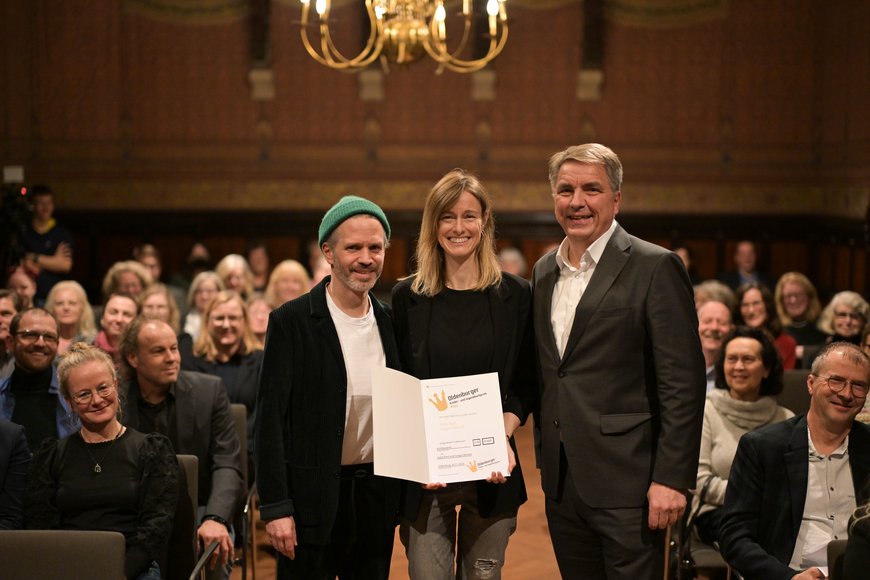 Oberbürgermeister Jürgen Krogmann mit den beiden Preistragenden vor dem Publikum. Foto: Mohssen Assanimoghaddam 