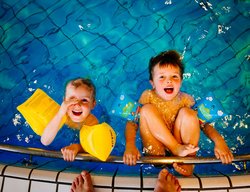 Zwei Kinder am Beckenrand im Wasser. Foto: tookapic/Pixabay