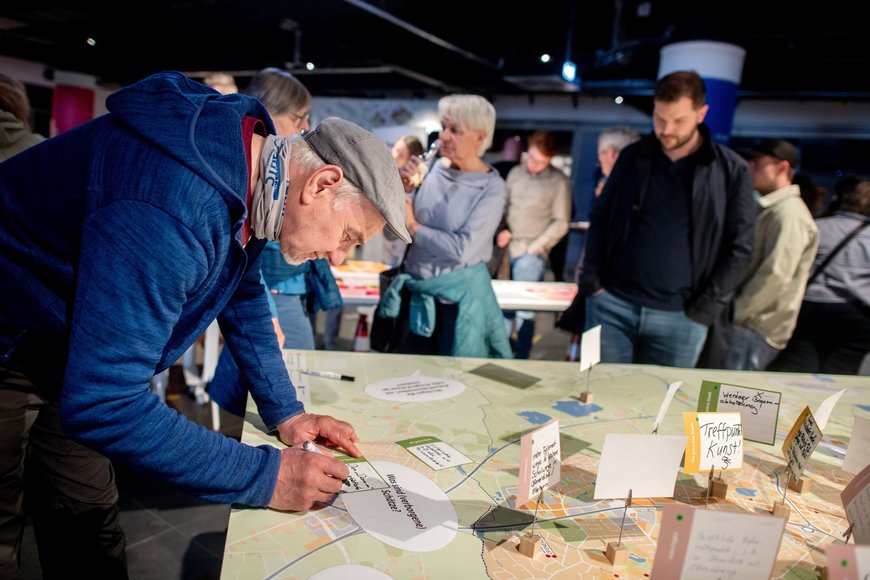 Ein Herr notiert auf einen Zettel eine Antwort auf die Frage „Was sind (verborgene) Schätze? Foto: Hauke-Christian Dittrich