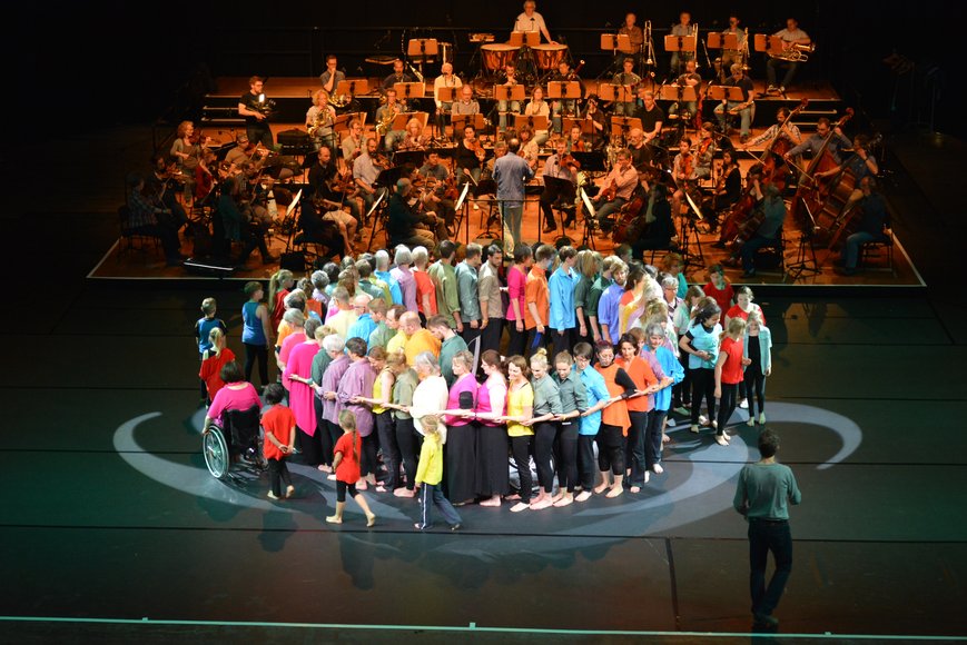 Szenenfoto großes Gruppenbild mit Orchester. Foto: Jörg Sarbach
