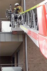 Ausgefahrene Leiter eines Feuerwehrfahrzeugs mit einem Feuerwehrmann an einem Balkon. Foto: Stadt Oldenburg